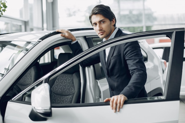 Hombre guapo y elegante en un salón del automóvil