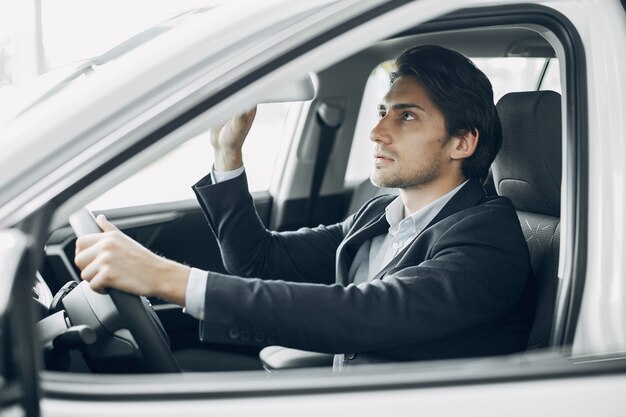 Hombre guapo y elegante en un salón del automóvil