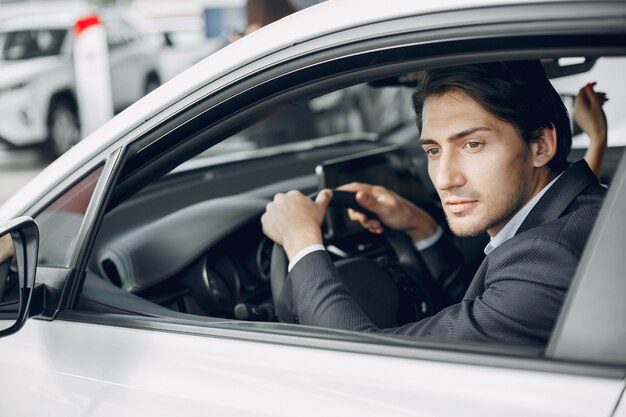 Hombre guapo y elegante en un salón del automóvil