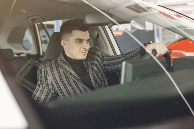 Hombre guapo y elegante en un salón del automóvil