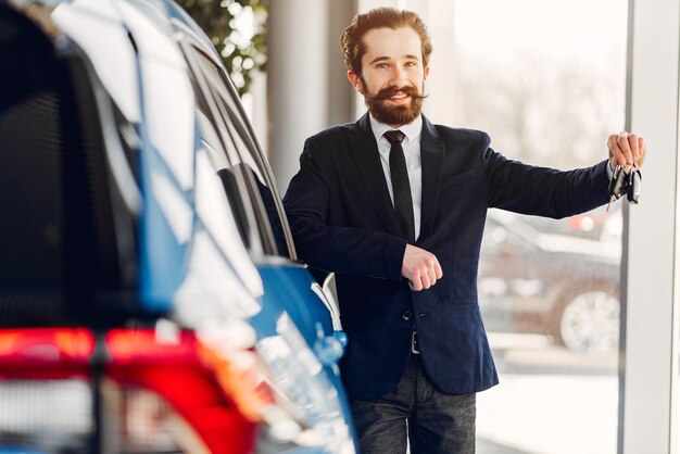 Hombre guapo y elegante en un salón de autos.