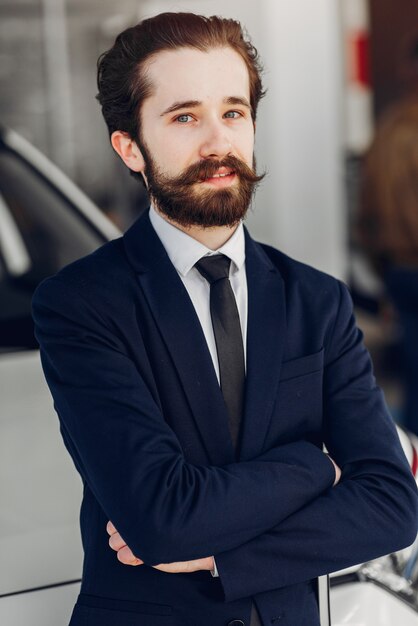 Hombre guapo y elegante en un salón de autos.