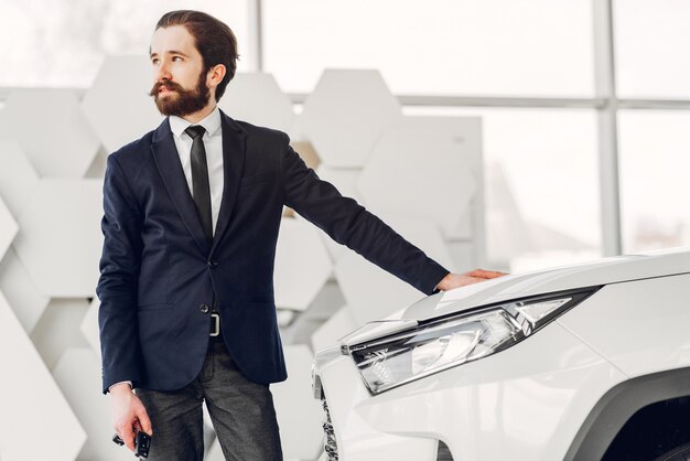 Hombre guapo y elegante en un salón de autos.