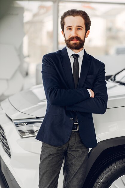 Hombre guapo y elegante en un salón de autos.