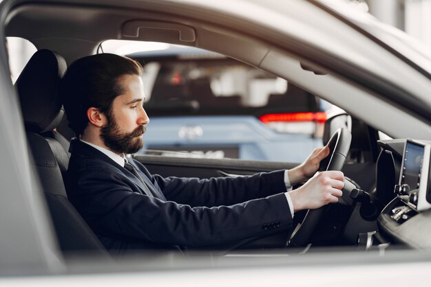 Hombre guapo y elegante en un salón de autos.