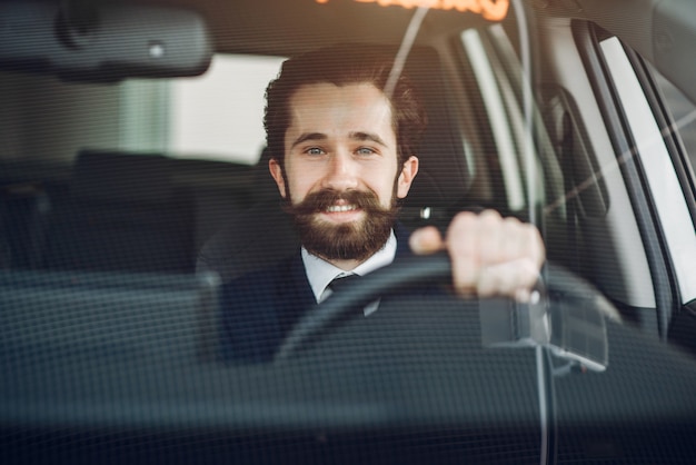 Hombre guapo y elegante en un salón de autos.