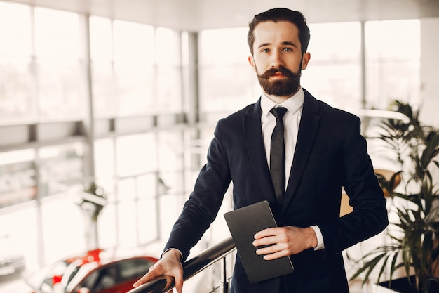 Foto gratuita hombre guapo y elegante en un salón de autos.