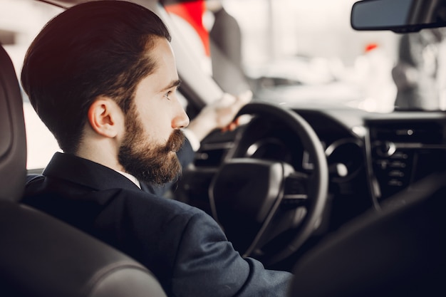 Hombre guapo y elegante en un salón de autos.