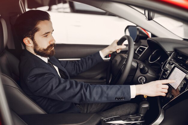 Hombre guapo y elegante en un salón de autos.