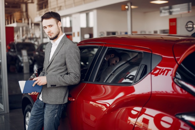 Hombre guapo y elegante en un salón de autos.