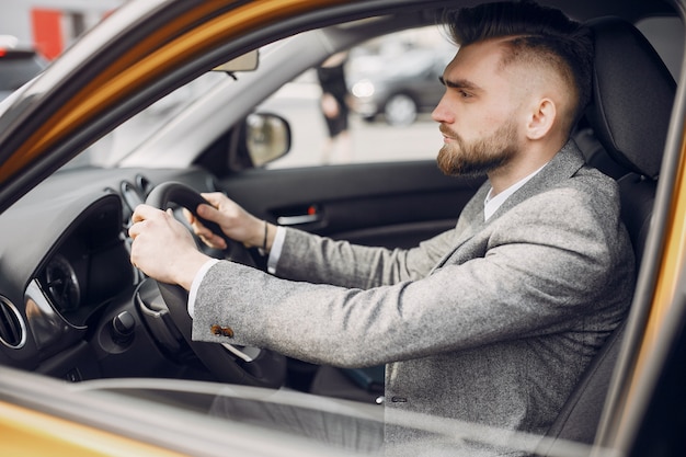 Hombre guapo y elegante en un salón de autos.