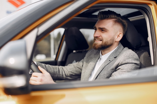 Hombre guapo y elegante en un salón de autos.