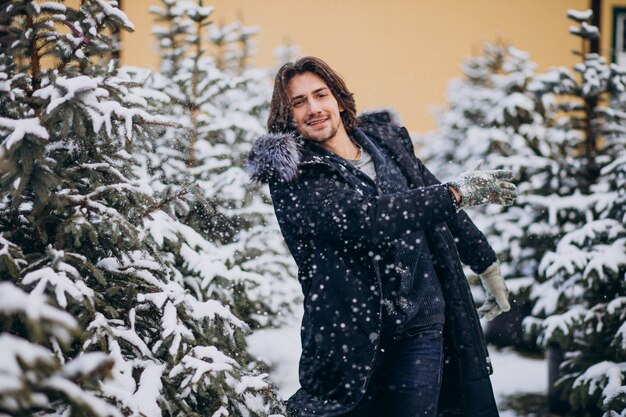 Hombre guapo eligiendo un árbol de navidad