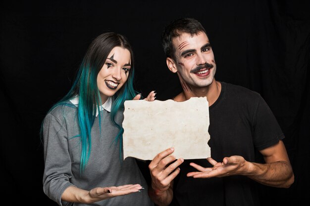 Hombre guapo con encantadora mujer sosteniendo la hoja de papel