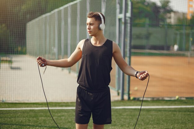 Hombre guapo entrenando en un parque de verano con una cuerda de saltar