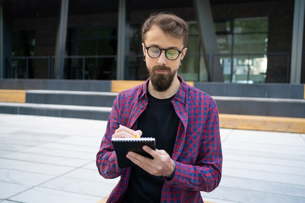 Foto gratuita hombre guapo escribiendo en cuaderno con lápiz