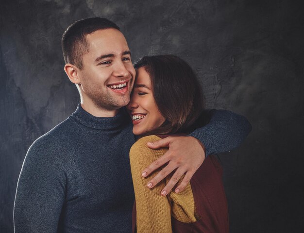 Un hombre guapo está abrazando a su atractiva mujer feliz en el estudio fotográfico.