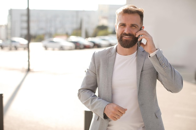 hombre guapo en estilo casual con teléfono móvil con barba