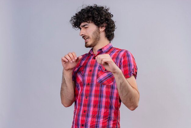 Un hombre guapo estresante con el pelo rizado en camisa a cuadros empujando con las manos