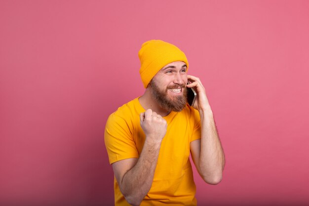 Hombre guapo europeo hablando por teléfono inteligente gritando orgulloso y celebrando la victoria y el éxito muy emocionado en rosa