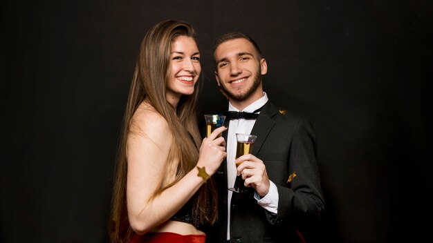 Hombre guapo feliz y atractiva mujer con copas de bebidas y confeti