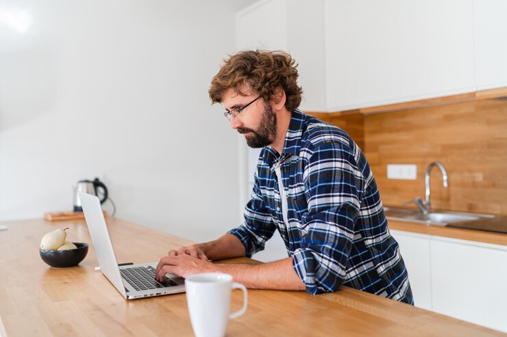 Foto gratuito hombre guapo freelance usando portátil estudiando en línea trabajando desde casa