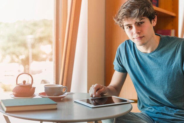 Hombre guapo con gadget sentado en la mesa