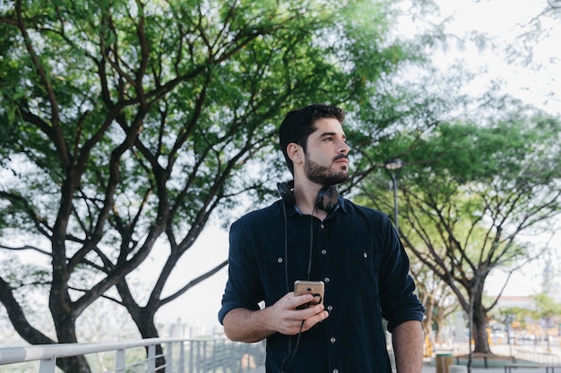 Hombre guapo con gadgets en el parque