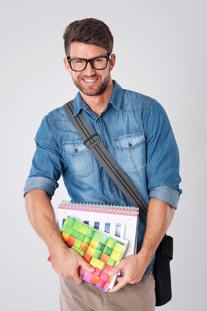 Hombre guapo con gafas de moda y gorro de lana con cuaderno y mochila escolar