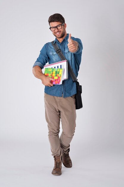 Hombre guapo con gafas de moda y gorro de lana con cuaderno y mochila escolar