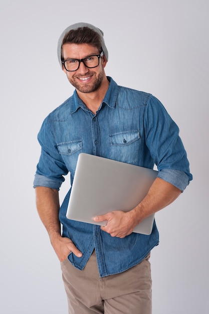 Hombre guapo con gafas de moda y gorro de lana con portátil