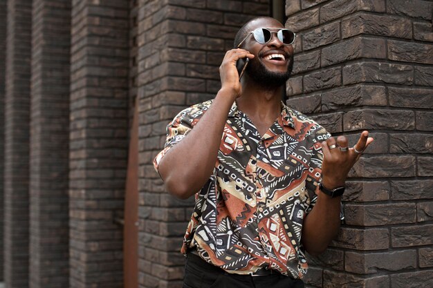 Hombre guapo con gafas de sol con smartphone moderno al aire libre