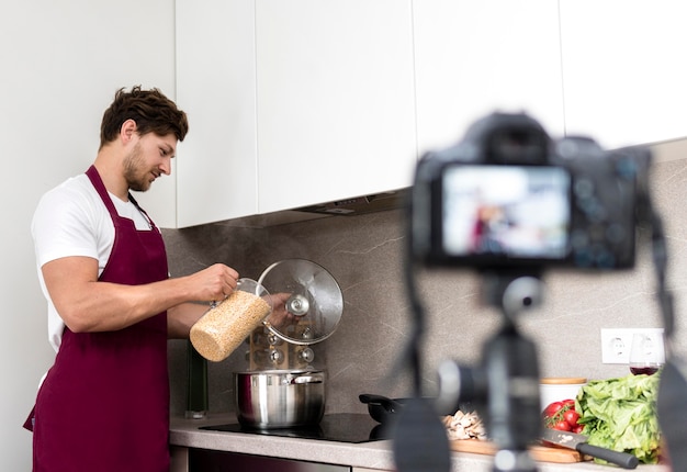 Hombre guapo grabando video de cocina en casa