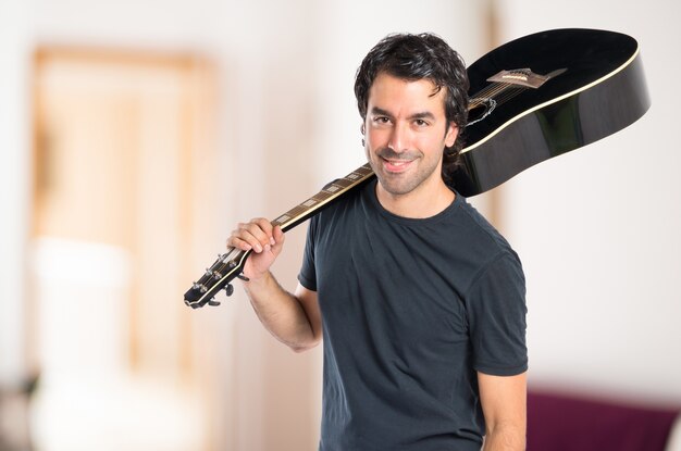 Hombre guapo con la guitarra sobre fondo blanco