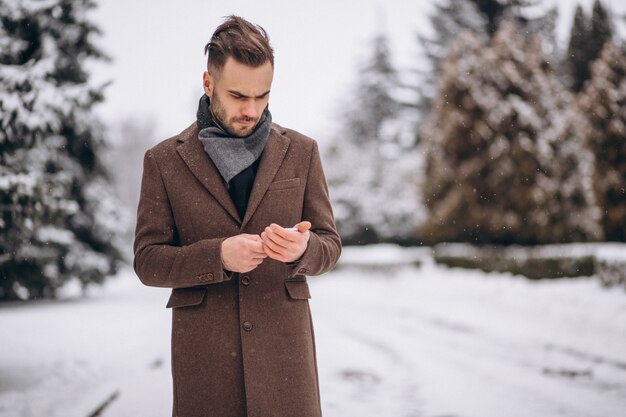 Hombre guapo hablando por teléfono en un parque de invierno