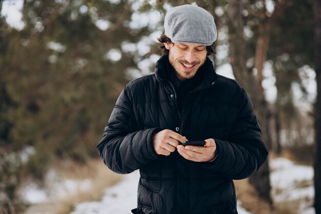 Hombre guapo hablando por teléfono en un parque de invierno