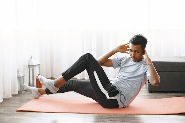 Hombre guapo haciendo ejercicios de abdominales en casa. Concepto de vida sana.