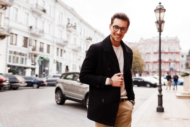 Hombre guapo hermoso sonriente en chaqueta posando en la calle. Tendencias de la moda masculina de otoño.
