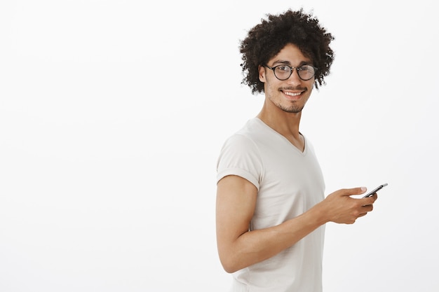 Hombre guapo hipster en gafas sosteniendo smartphone y sonriendo