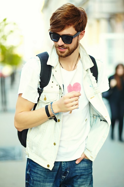 Hombre guapo inconformista sonriente divertido en tela elegante de verano en la calle con gafas de sol