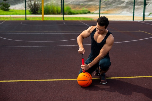 Hombre guapo inflar una pelota bajo ángulo de tiro