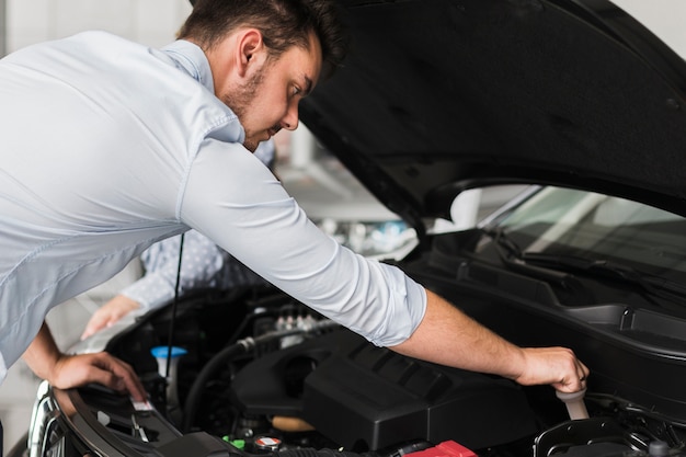 Hombre guapo inspeccionando el motor del automóvil