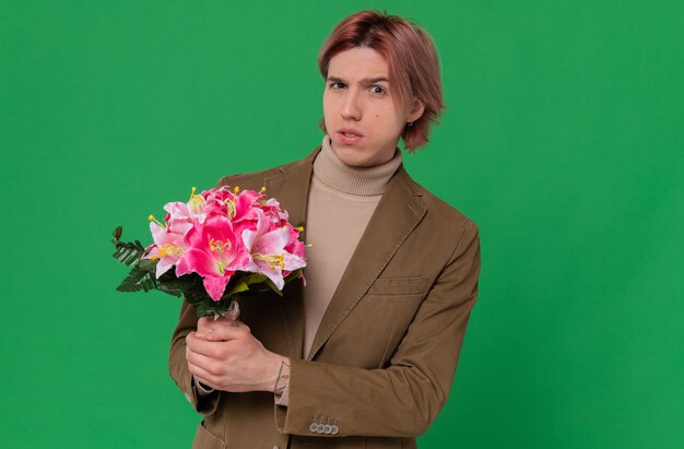 Hombre guapo joven ansioso con ramo de flores y mirando