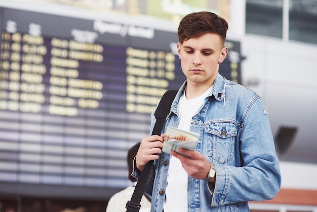 Hombre guapo joven con una bolsa en el hombro a toda prisa hacia el aeropuerto.