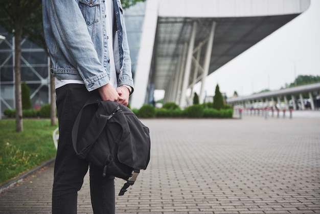 Hombre guapo joven con una bolsa en el hombro a toda prisa hacia el aeropuerto.