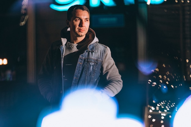 Hombre guapo joven caminando por la noche fuera de la calle