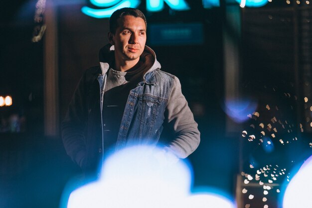 Hombre guapo joven caminando por la noche fuera de la calle