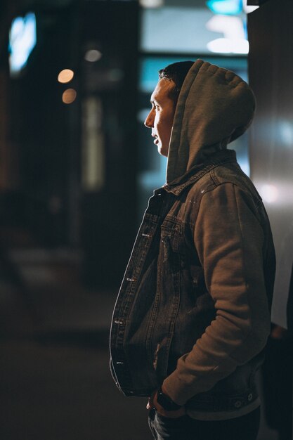 Hombre guapo joven caminando por la noche fuera de la calle