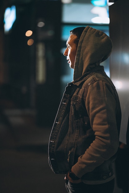 Hombre guapo joven caminando por la noche fuera de la calle