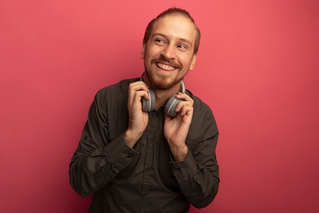 Hombre guapo joven en camisa gris con auriculares mirando a un lado sonriendo alegremente